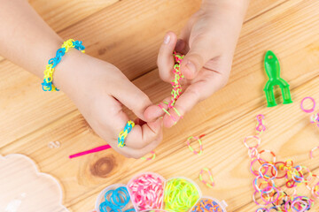 Hands of a girl weaving a bracelet with multi-colored rubber bands. Development of fine motor skills of fingers