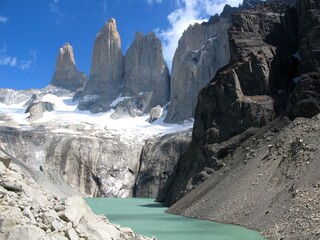 Iconic Torres del Paine granite towers above a turquoise glacial lake in the rugged Patagonian wilderness.