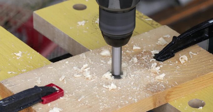 DIY reclaimed wood, drilling hole at wood plank using battery powered electric drill and forstner bit, close up