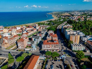 Aerial view of buildings basking under the sun near the azure sea, the port extending into the distance, a harmonious blend of urban and coastal beauty, Termoli, Molise, Italy.