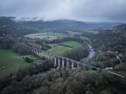 Aerial view of the majestic, stone-pillared aqueduct cuts a path through the autumn-toned landscape, under a low, brooding sky, Llangollen, Wales, United Kingdom.