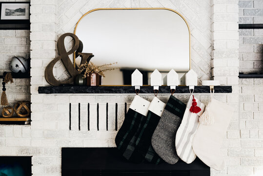 Modern Christmas Stockings on White Brick Fireplace with Mirror and Holiday Decor