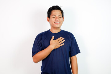 Smiling Man With Hand On Chest In A Calm, Peaceful Pose Wearing Navy T-Shirt