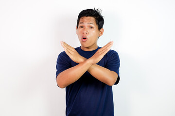 A man in a dark blue shirt stands against a plain white backdrop, crossing his arms in an X gesture with a surprised expression. Ideal for denial, stop, warning, or boundary concepts.