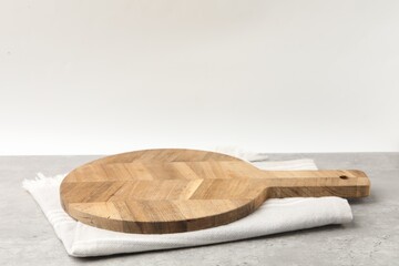 Wooden cutting board and napkin on grey table