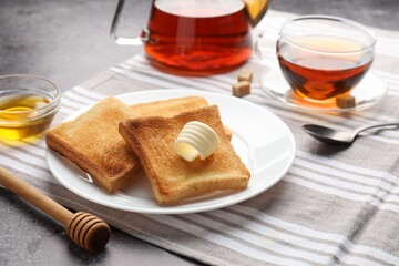 Fresh toasted bread slices with butter, honey and tea on table