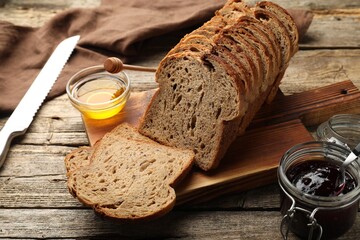 Bread slices with honey and jam on wooden table
