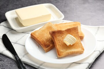 Fresh toasted bread slices with butter on grey table, closeup