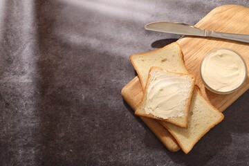 Bread slices with butter on grey table, top view. Space for text