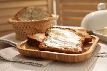 Bread slices with butter on white wooden table, closeup