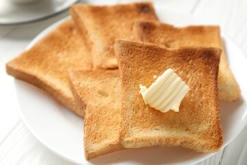 Fresh toasted bread slices with butter on white wooden table, closeup