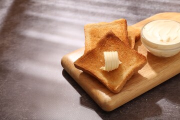 Fresh toasted bread slices with butter on grey table, closeup. Space for text