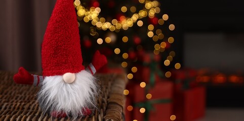 Obraz premium Funny Christmas gnome in decorated room, closeup. Space for text
