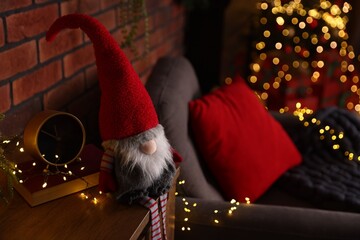 Obraz premium Funny Christmas gnome on cabinet in decorated room, closeup. Space for text