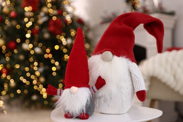 Obraz premium Funny Christmas gnome on white table in decorated room, closeup