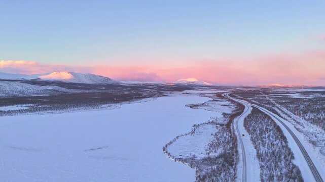 Sunset over a road passing through arctic mountains landscape in Lapland, Sweden, between Kiruna and Abisko