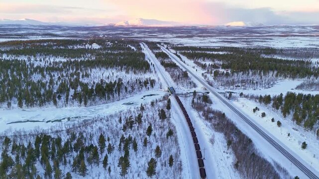 Freight train with iron ore, aerial view, Sunset over arctic mountain landscape in Lapland, Sweden, road and railroad between Kiruna and Narvik