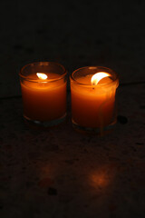 A candle burned on a glass holder in the dark, a symbol of hope.	