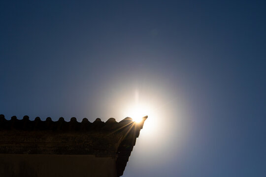 Sunlight shining behind the rooftop edge creating a radiant starburst effect, Portugal, Ovar &ndash; Furadouro, 10.10.2025