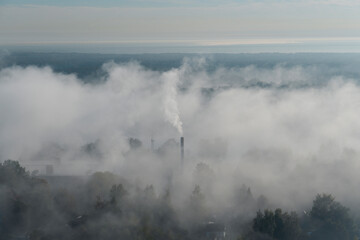 Fog covers the area while smoke rises from factory stacks. The scene captures an industrial landscape shrouded in mist during early morning hours