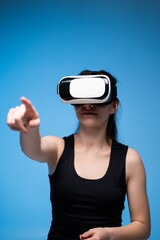 Woman wearing VR headset pointing forward while interacting with immersive futuristic digital environment