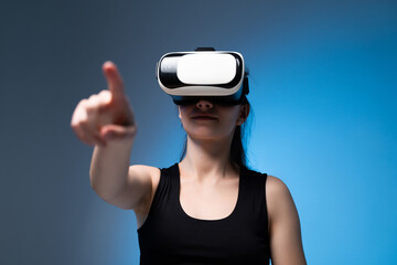 Young woman reaching forward while using VR headset in immersive digital environment with blue lighting