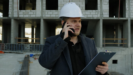 Construction talking on a smartphone while overlooking the busy work site