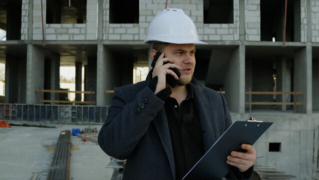 Male construction manager talking seriously on the phone at the job site - Powered by Adobe