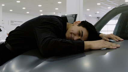 Tired customer lying face down on the hood of a car,