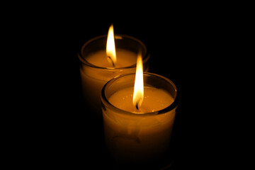 A candle burned on a glass holder in the dark, a symbol of hope.	