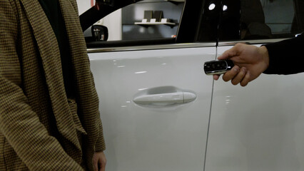 Close-up shot of a man opening the white car door for a client in the showroom