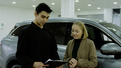 Sales manager and couple discussing the car purchase details in the showroom