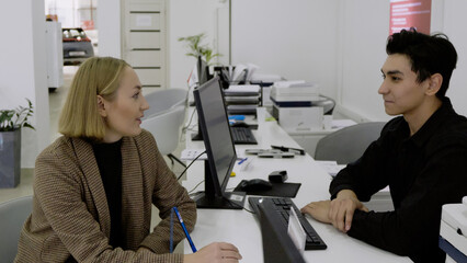 Manager and clients sitting at a desk, finalizing paperwork for a car purchase