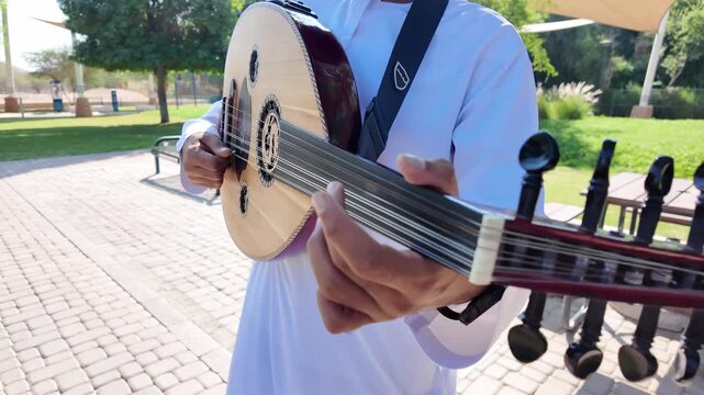 A person playing an oud, a prominent stringed instrument in Middle Eastern music at celebration of The United Arab Emirates Independence Day ( 54th uae national day ) in Al Ain Zoo	
