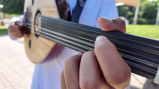 A person playing an oud, a prominent stringed instrument in Middle Eastern music at celebration of The United Arab Emirates Independence Day ( 54th uae national day ) in Al Ain Zoo	