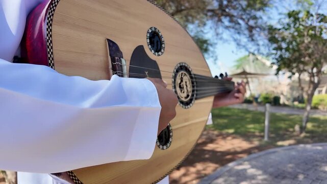 A person playing an oud, a prominent stringed instrument in Middle Eastern music at celebration of The United Arab Emirates Independence Day ( 54th uae national day ) in Al Ain Zoo	