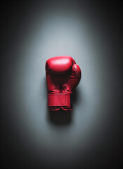Red boxing glove on dark background with soft lighting  