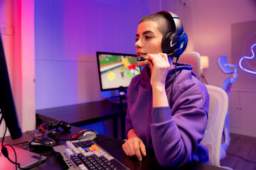 Confident young woman with a buzzcut in a purple hoodie gaming or working at a colorful setup. Perfect for LGBTQ representation in tech, esports, streaming, or modern digital lifestyle.