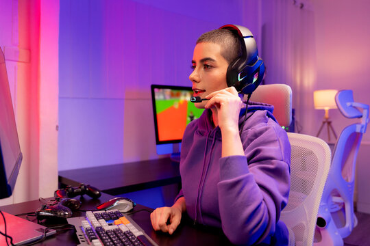 Confident young woman with a buzzcut in a purple hoodie gaming or working at a colorful setup. Perfect for LGBTQ representation in tech, esports, streaming, or modern digital lifestyle.