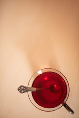 Vertical image from above, looking down at a teacup with a silver spoon.