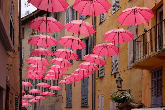 Fototapeta Streets of Grasse, a city known for its perfumery, decorated with pink umbrellas on the occasion of the annual international exhibition of roses - Expo Rose.