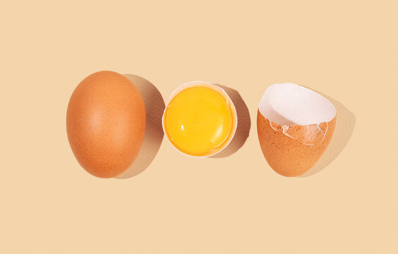 An artistic composition of brown eggs on a yellow background with one cracked egg