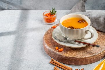 Sea buckthorn herbal tea in a cup on a wooden board on a light background