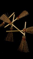 Mini witch brooms on black background, occult props, mystical composition, esoteric tools for magic and rituals