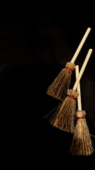 Mini witch brooms on black background, occult props, mystical composition, esoteric tools for magic and rituals