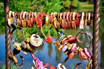 A metal railing is densely covered with numerous «love locks».  Different types of locks on a metal fence in a park. for romantic-themed content, wedding websites, travel blogs
