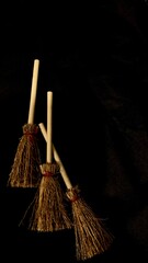 Mini witch brooms on black background, occult props, mystical composition, esoteric tools for magic and rituals