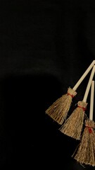 Mini witch brooms on black background, occult props, mystical composition, esoteric tools for magic and rituals