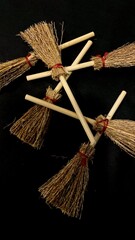 Mini witch brooms on black background, occult props, mystical composition, esoteric tools for magic and rituals