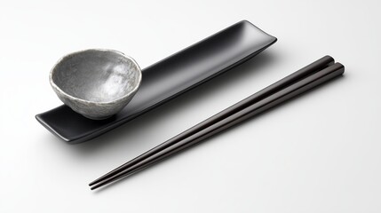 Elegant black plate and bowl set with wooden chopsticks on a light background